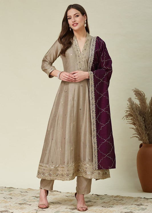 Woman wearing a beige and purple traditional outfit with a neutral background