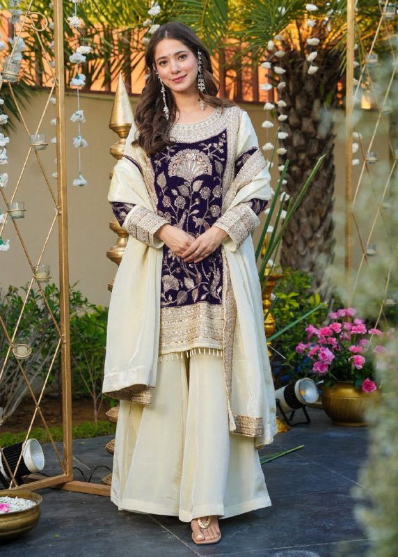 Woman in traditional outfit standing in a decorative outdoor setting with plants and flowers.
