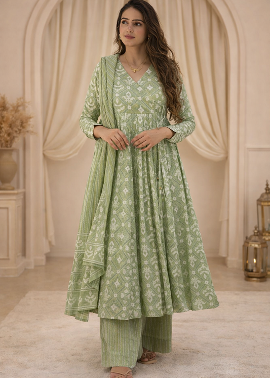 Woman wearing a green traditional outfit with a floral pattern in an elegant indoor setting.