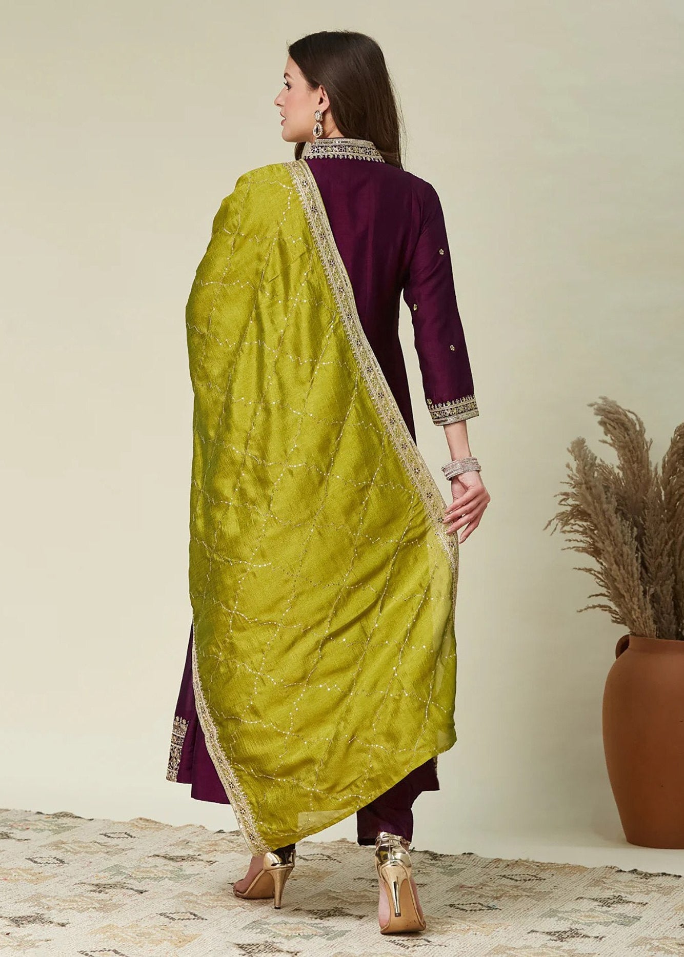Woman wearing a green saree with a purple blouse against a neutral background