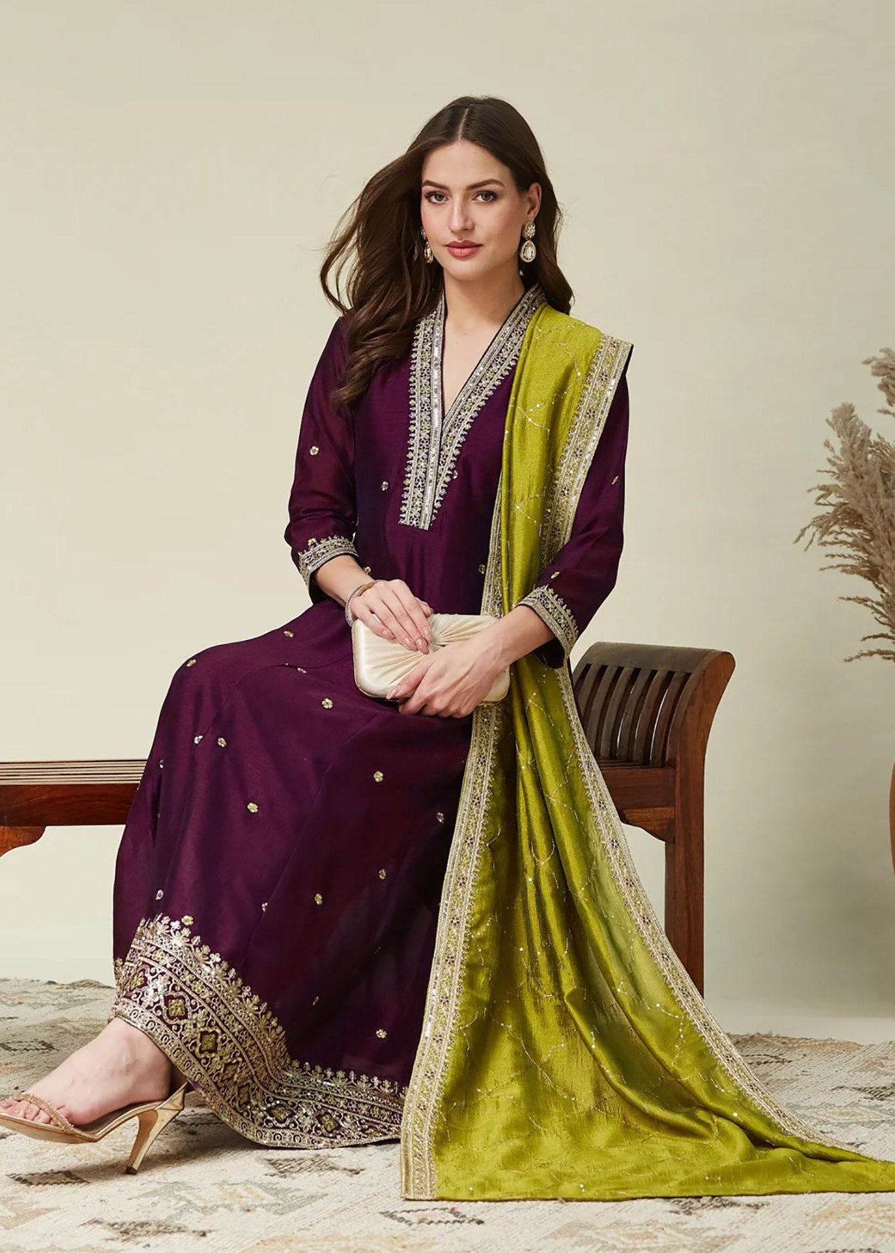 Woman in a purple and green traditional outfit with a plain background