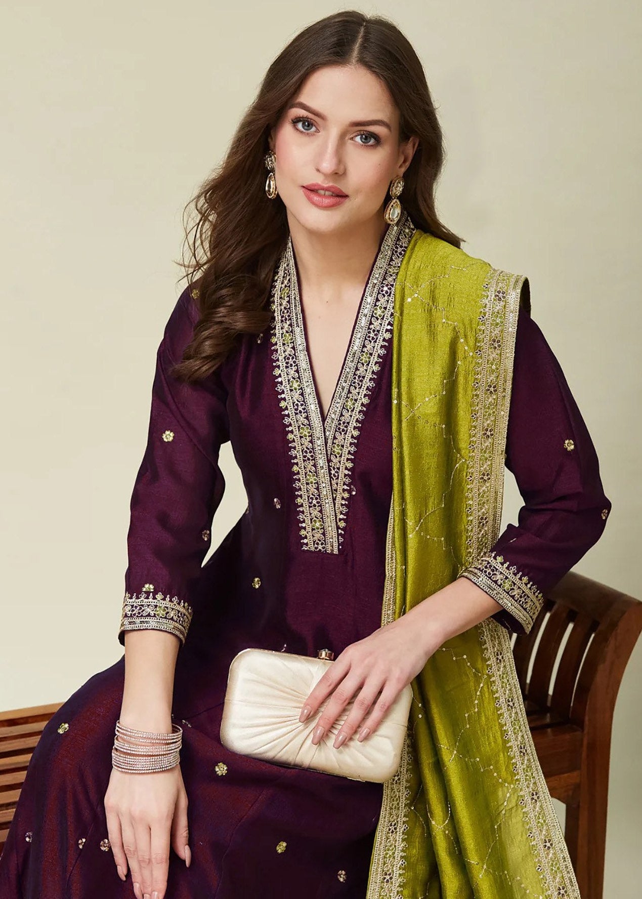 Woman wearing a purple and green traditional outfit with a beige background