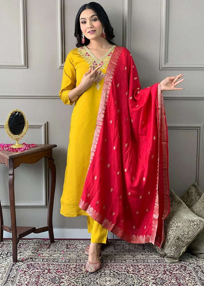 Woman wearing a mustard yellow embroidered Tesla Cotton kurta with matching pants and a vibrant pink Chanderi Jacquard dupatta featuring woven motifs and decorative border, perfect for festive and traditional occasions.
