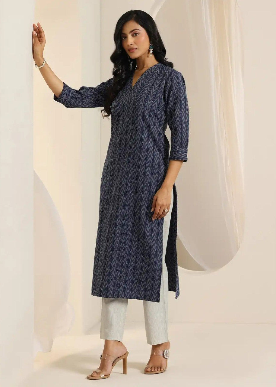Woman wearing a blue patterned kurta with white pants against a neutral background