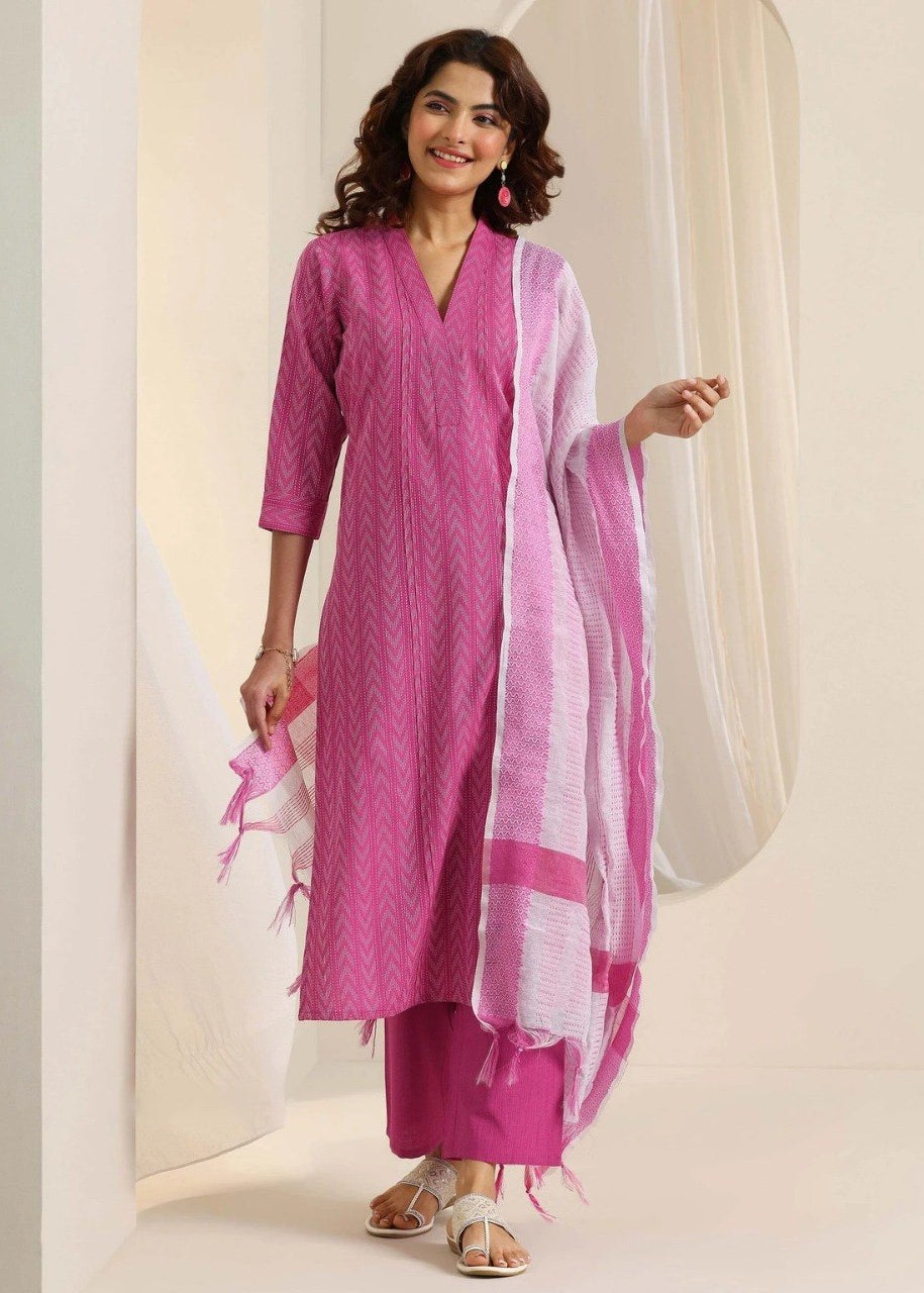 A woman models a traditional Indian salwar kameez set in pink, featuring a pink kurta with a white chevron pattern, matching pink trousers, and a white and pink patterned dupatta.